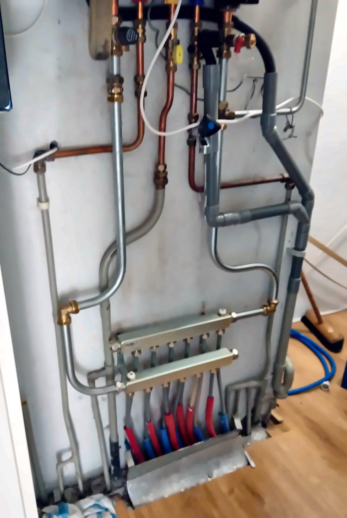 Verdeler voor vloerverwarming in een kast, met rode en blauwe leidingen die de vloer in gaan